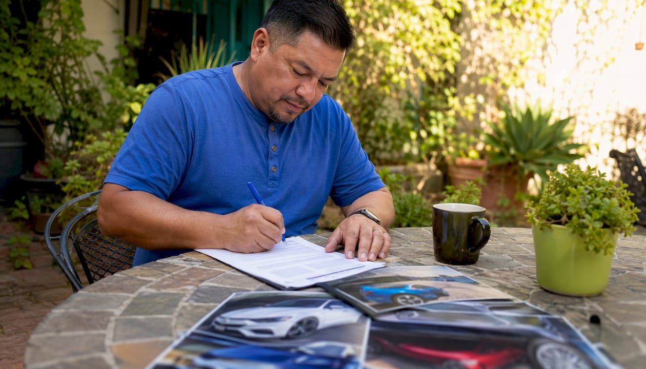 Man completing salvage car sale paperwork at home desk
