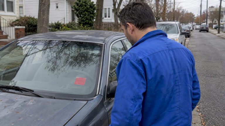 Owner examining failed inspection sticker on car